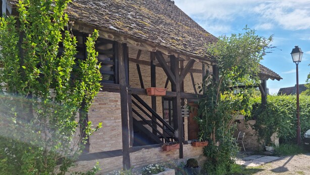 A traditional half-timbered house with a wooden staircase leading to the entrance, surrounded by greenery and a cobblestone path. - Bienvenue à l'escale (Gigny-sur-Saône)