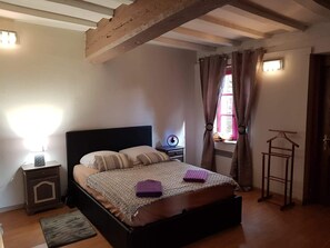 Ein Schlafzimmer mit einem Bett, einer Nachttischlampe und einem Fenster mit Vorhängen.