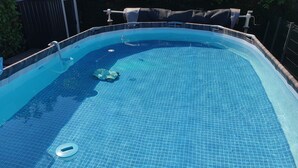 A clear blue swimming pool with a tiled floor, a pool ladder, and a pool cover. - Bienvenue à l'escale (Gigny-sur-Saône)
