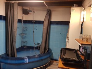 Ein Badezimmer mit einer blauen Duschkabine, einer Badewanne und einem Waschbecken mit Wasserhahn.