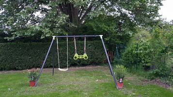 Relax in a serene outdoor space with a sturdy swing set and lush greenery.