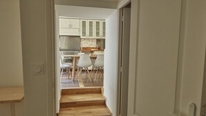Un escalier menant à une cuisine avec des meubles blancs et un coin repas équipé de chaises.