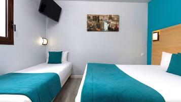 Ein Hotelzimmer mit zwei Betten, einem an der Wand montierten Fernseher und einem Bild der Freiheitsstatue.