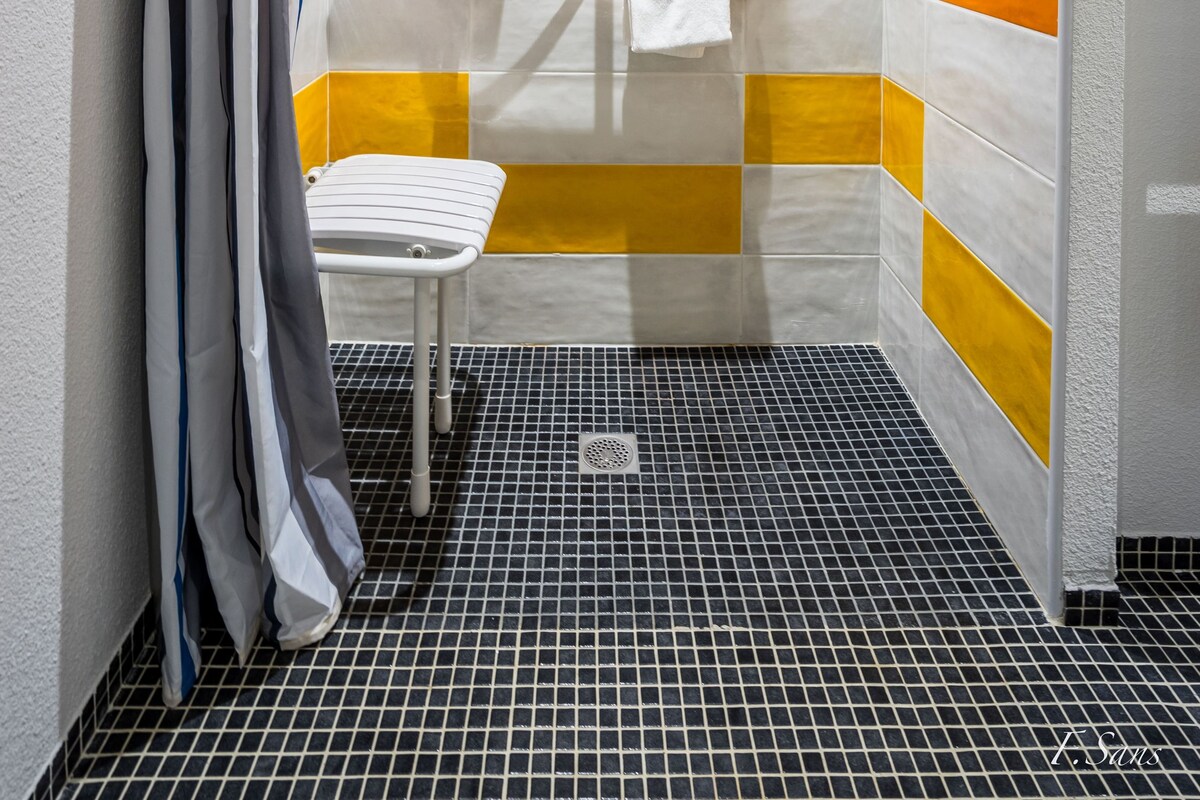 A small, tiled shower with a white toilet and a towel rack.