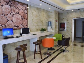 A reception area with a marble wall, a computer, a water dispenser, and several chairs. - Greentree Inn (Xuzhou Railway Station) (Xuzhou)
