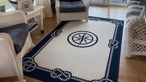 Un salon chaleureux avec un fauteuil en osier, un canapé et une grande fenêtre agrémentée de rideaux.