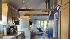 Une cuisine avec des meubles de rangement en bois, un four encastré et une grande fenêtre.