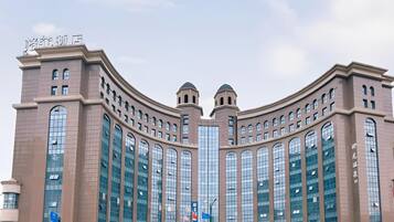 Ein großes, modernes Gebäude mit einer geschwungenen Fassade, zahlreichen Fenstern und einem markanten Eingang.