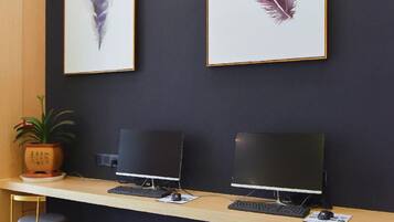 A reception desk with two computer monitors, a potted plant, and two bar stools.