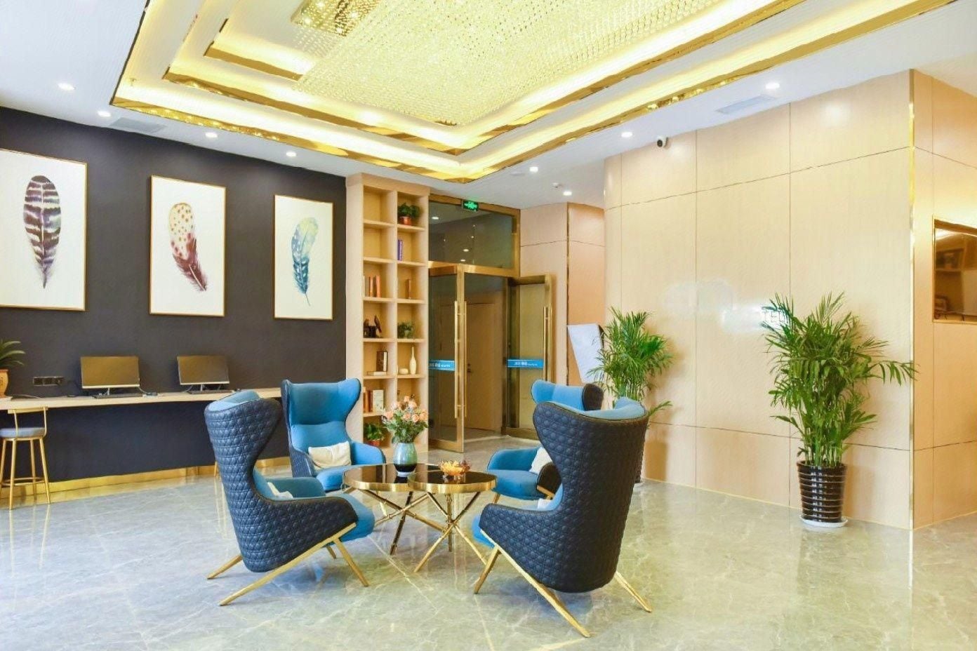 Un lobby moderno con una recepción, dos sillones azules, una mesa de centro y un techo decorativo.