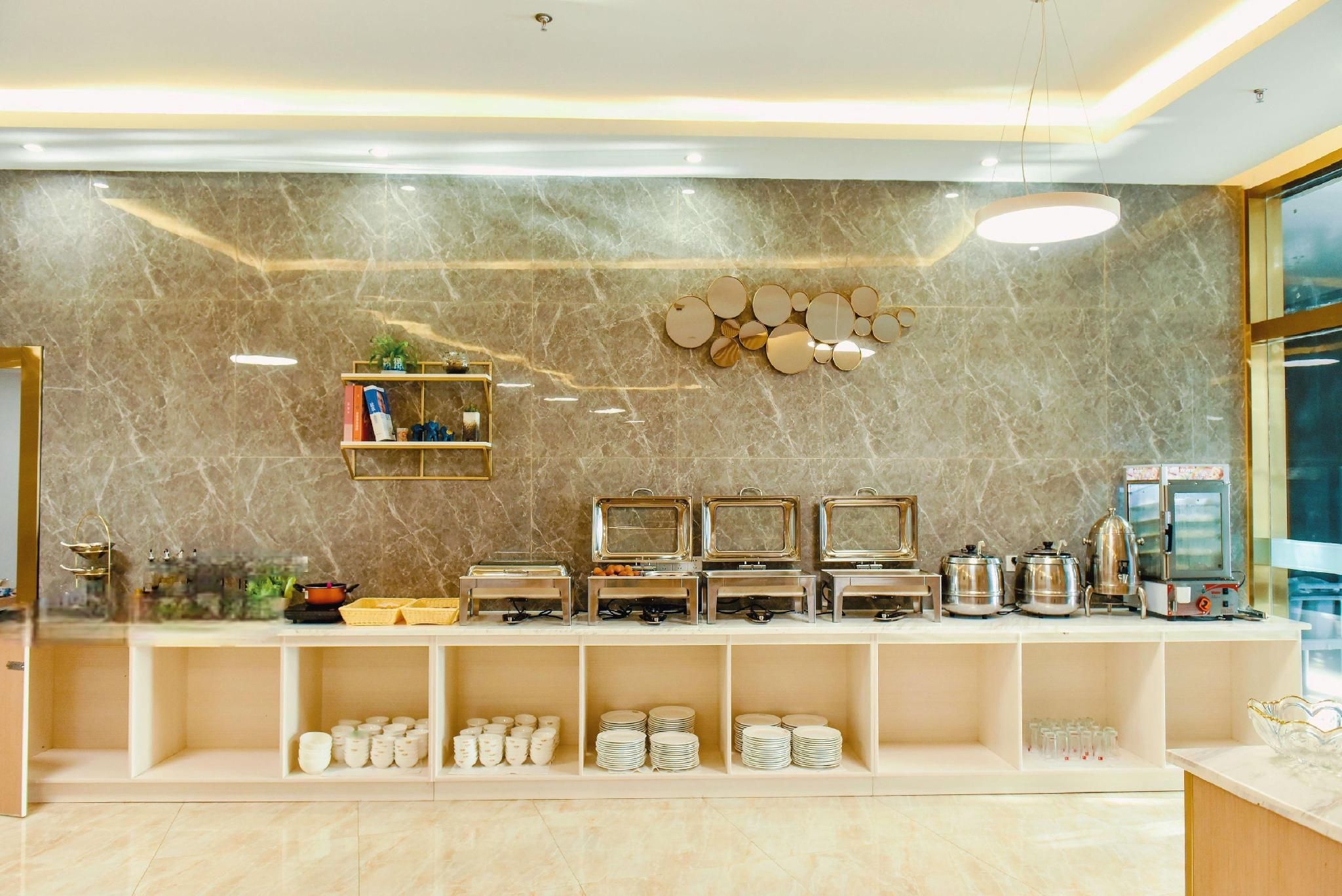 A buffet setup with multiple serving stations, a marble wall, and a modern light fixture.