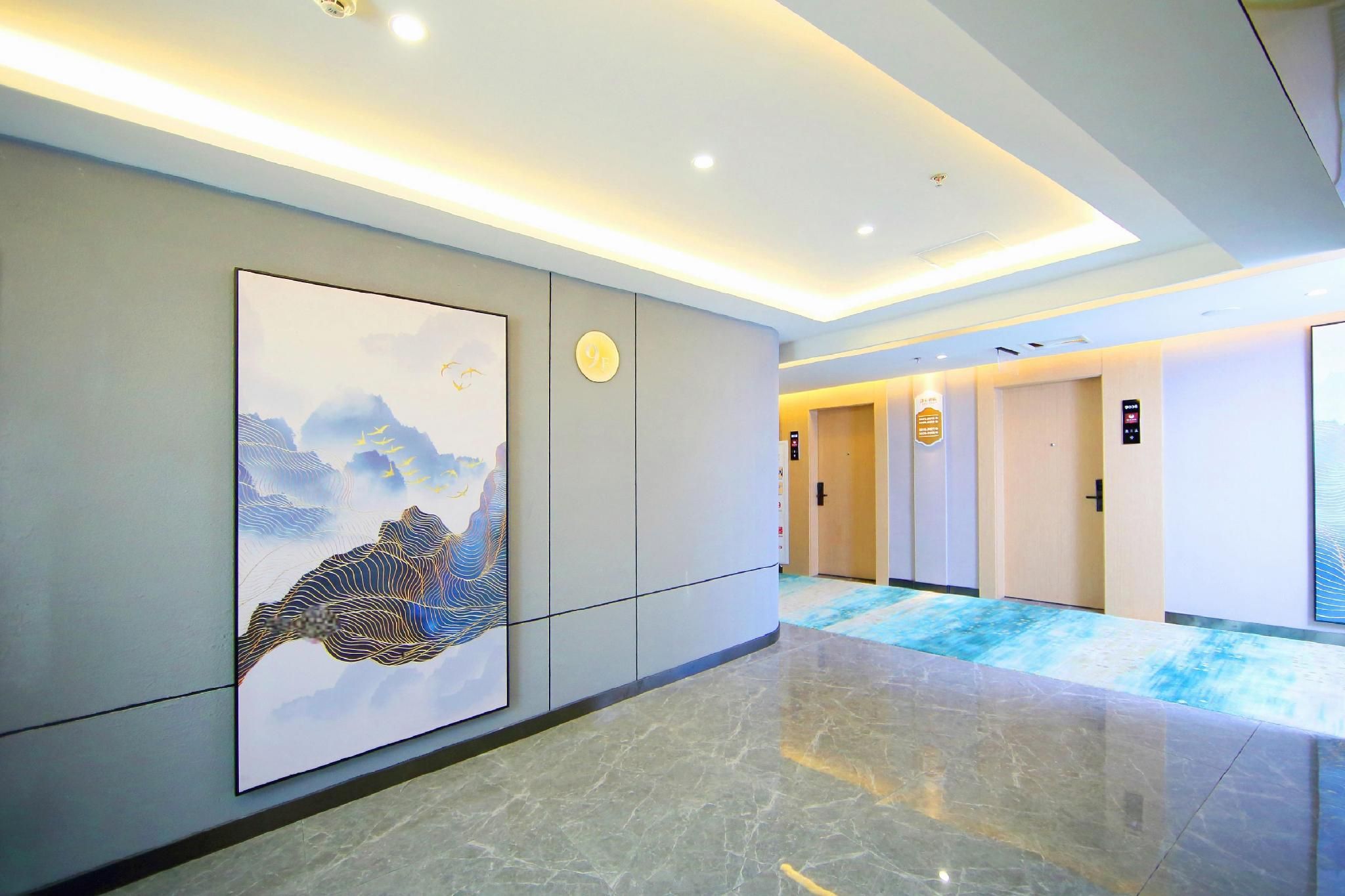 Corredor de hotel com uma grande obra de arte na parede, piso lustroso e portas de acesso aos quartos.