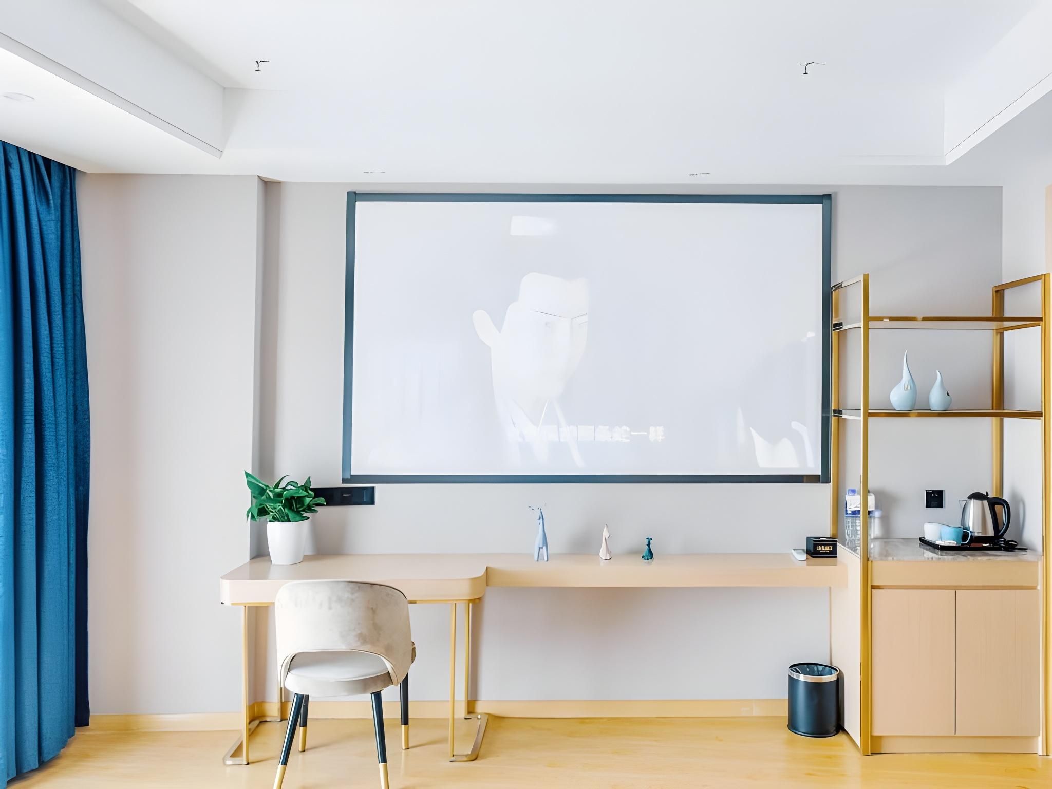 Ein modernes Zimmer mit Schreibtisch, Stuhl und einer Projektorleinwand, die ein weißes Bild zeigt.