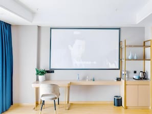 A modern room with a desk, chair, and a projector screen displaying a white image.