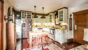 A kitchen with white cabinets, a wooden table, and a patterned rug. - Historic Luxury Condo with POOL & modern amenities in Wildwood Crest, NJ   (Wildwood Crest)