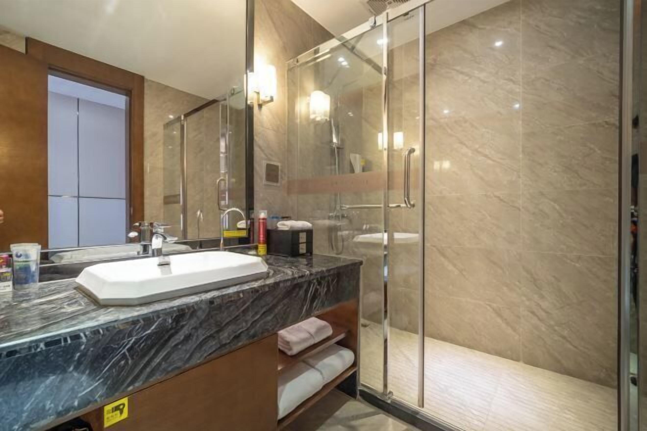 Ein modernes Badezimmer mit Marmorwaschbecken, einer Duschkabine aus Glas und einem Holzbadezimmer-Möbel.