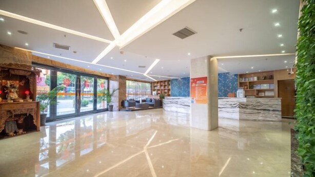 A modern lobby with a marble reception desk, a seating area, and a large window with a view of greenery outside. - Ruiting Hotel (Zhongshan Xiaolan Daxin Xinduhui Branch) (Zhongshan)