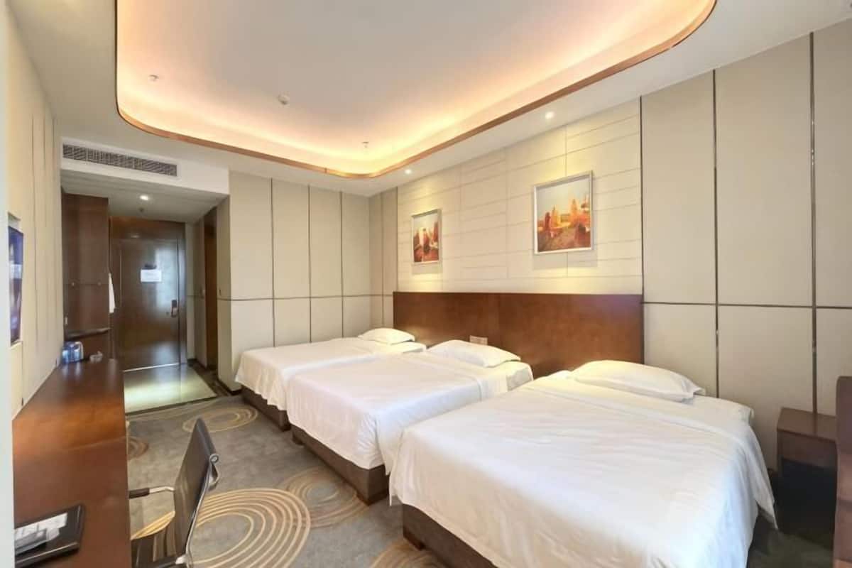 A hotel room with two beds, a desk, and a chair.