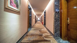 A hotel hallway with a carpeted floor, framed pictures on the walls, and a door with a number sign. - Ruiting Hotel (Zhongshan Xiaolan Daxin Xinduhui Branch) (Zhongshan)