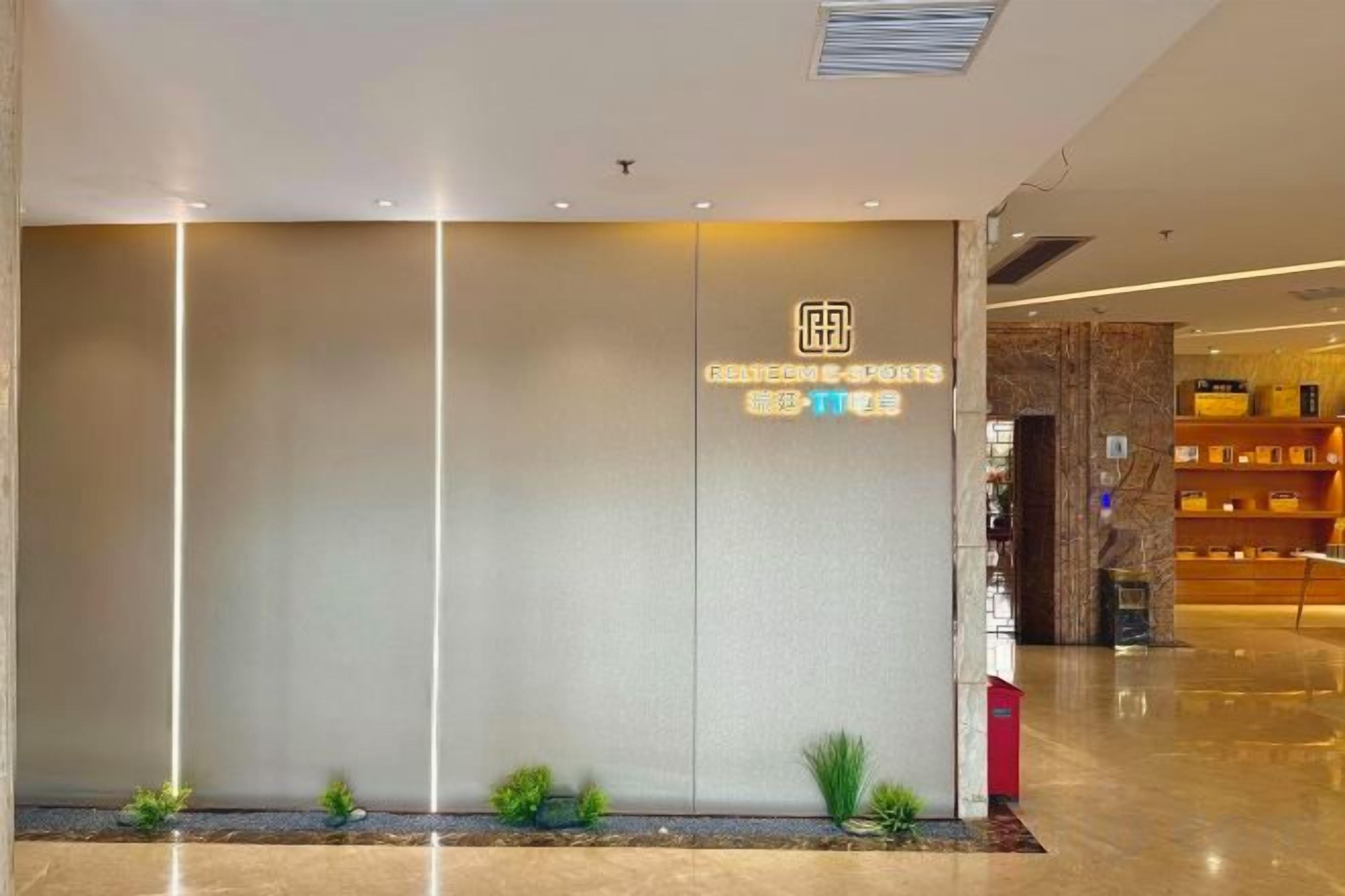 A modern hotel lobby with a reception desk, a marble wall, and a well-lit interior.
