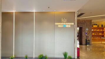 A modern hotel lobby with a reception desk, a marble wall, and a well-lit interior.