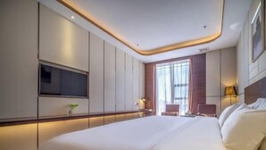 A modern hotel room with a large bed, a flat-screen TV mounted on the wall, a small desk, and a window with curtains. - Ruiting Hotel (Zhongshan Xiaolan Daxin Xinduhui Branch) (Zhongshan)