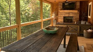 A wooden deck with a table and benches, a fireplace, and a TV mounted on the wall. - BUDDHA BLUE RIDGE TREES is a BRAND NEW custom 4/4 Close to town Find your ZEN... (Blue Ridge)
