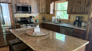 A kitchen with wooden cabinets, a granite countertop, stainless steel appliances, and a window with a view of trees. - BUDDHA BLUE RIDGE TREES is a BRAND NEW custom 4/4 Close to town Find your ZEN... (Blue Ridge)