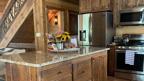 A wooden kitchen with a central island, stainless steel appliances, and a staircase leading to an upper level. - BUDDHA BLUE RIDGE TREES is a BRAND NEW custom 4/4 Close to town Find your ZEN... (Blue Ridge)