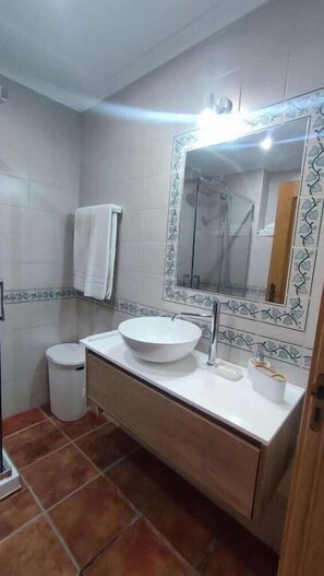 A bathroom with a white sink, a mirror with a decorative frame, a towel hanging on the wall, and a toilet. - Jardins Vale de Parra (Albufeira)