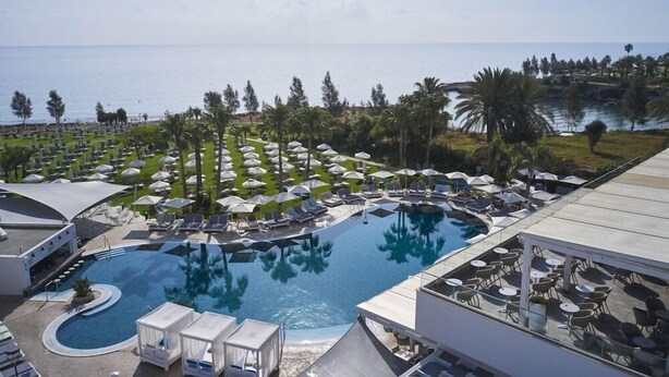 A resort with a large pool, sun loungers, umbrellas, and a view of the sea. - Atlantica Sea Breeze - Adults Only (Paralimni)