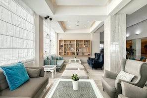 A modern living room with a sofa, armchairs, a coffee table, and a bookshelf. - Atlantica Sea Breeze - Adults Only (Paralimni)