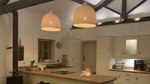 Una cocina moderna con una isla central, taburetes de bar e iluminación colgante.