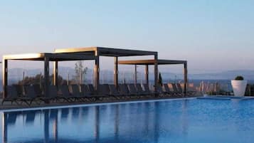 Piscina com espreguiçadeiras e área de estar coberta.