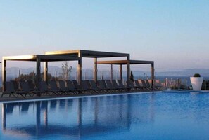 Piscina com espreguiçadeiras e área de estar coberta.