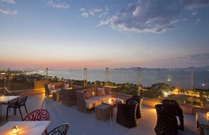 Une terrasse sur le toit avec des sièges en plein air, une vue sur la ville et un coucher de soleil.