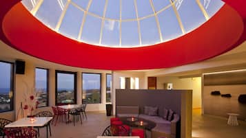 A modern interior with a skylight, large windows, a dining area, and a seating area.