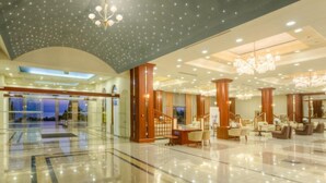 A spacious lobby with a reflective floor, a staircase, and a seating area with wooden furniture. - Kipriotis Panorama and Suites (Kos)