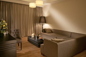 A modern living room with a sofa, armchair, and a coffee table with a bottle of champagne and candles.