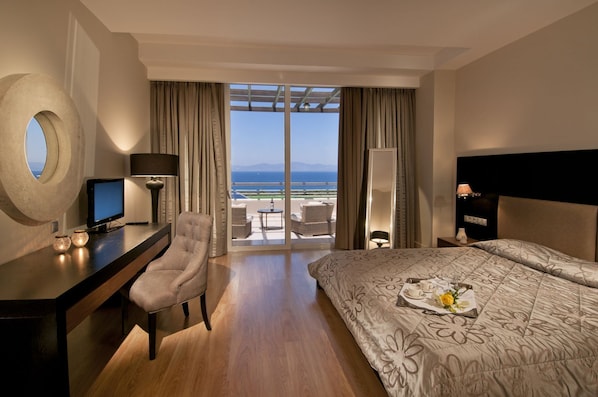 Habitación de hotel con cama, escritorio, silla y vistas al mar.
