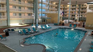 Una piscina interior con sillas de descanso y vistas a los balcones del edificio.