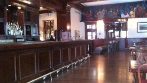 A bar area with wooden paneling, a counter, and a mural on the wall. - Le Meridien St Louis Downtown (St. Louis)