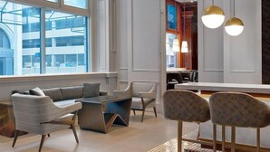 A modern hotel lobby with a seating area, a bar, and large windows offering views of the city. - Le Meridien St Louis Downtown (St. Louis)
