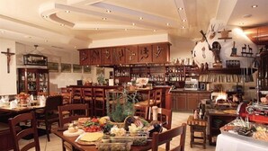 Un restaurante con muebles de madera, una zona de bar y varios platos sobre las mesas.