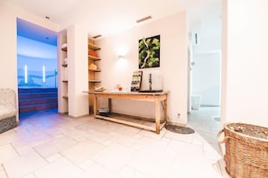 A hotel lobby with a wooden console table, a wall-mounted light, a framed picture, and a staircase leading to a balcony. - Hotel Feinschmeck (Zell am See)
