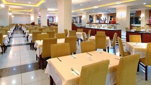 A spacious dining area with multiple tables and chairs, a central bar area, and a clean, well-lit environment. - Miarosa Konakli Garden (Alanya)