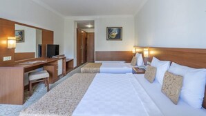 A hotel room with a bed, a desk, a chair, a television, and a painting on the wall. - Miarosa Konakli Garden (Alanya)