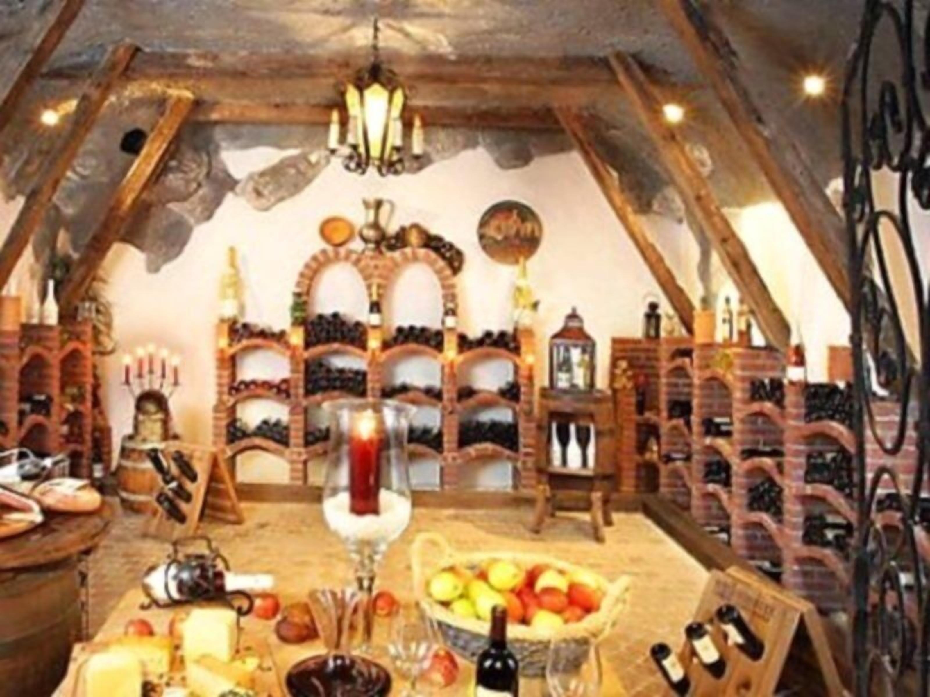 Ein rustikaler Keller mit Holzböden, einem Weinkühler und einem Tisch mit Speisen und Getränken.