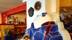 A room with a blue and white patterned sofa, a bar area with bottles, and a potted plant. - Schuetz (Untertauern)