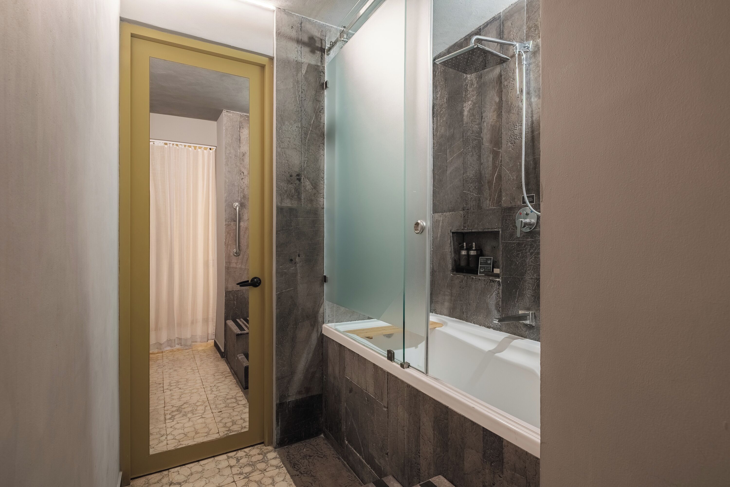 A bathroom with a shower, a bathtub, and a glass-enclosed mirror.